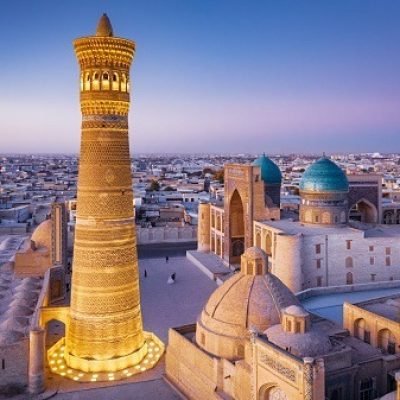 Colorful sunset twilight over the famous Old Town in the City of Bukhara with the iconic Kalyan Minaret and Miri Arab Madressa. Aerial Drone Point of View. Itchan Kala, Bukhara, Khorezm Region, Uzbekistan, Central Asia.